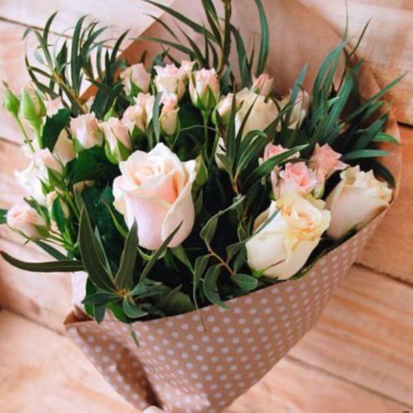 Bouquet of pale pink roses and small pink blooms in polka-dot wrap