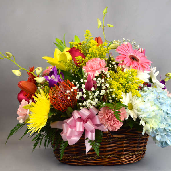 Colorful mixed flower basket with a pink ribbon bow