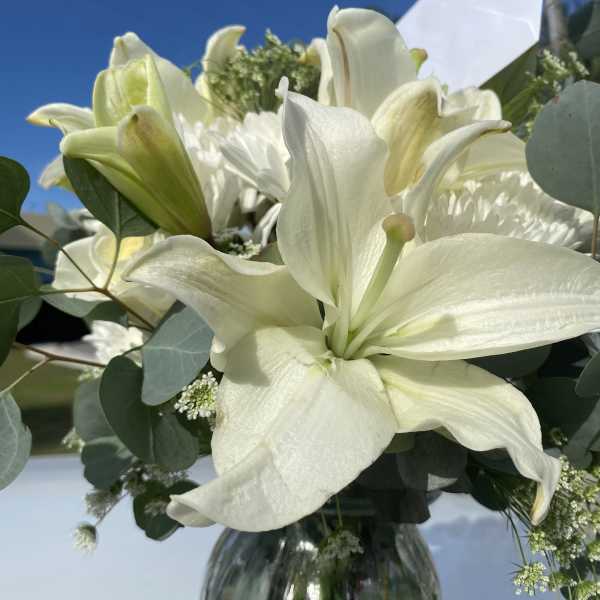 White lilies in a glass vase with eucalyptus