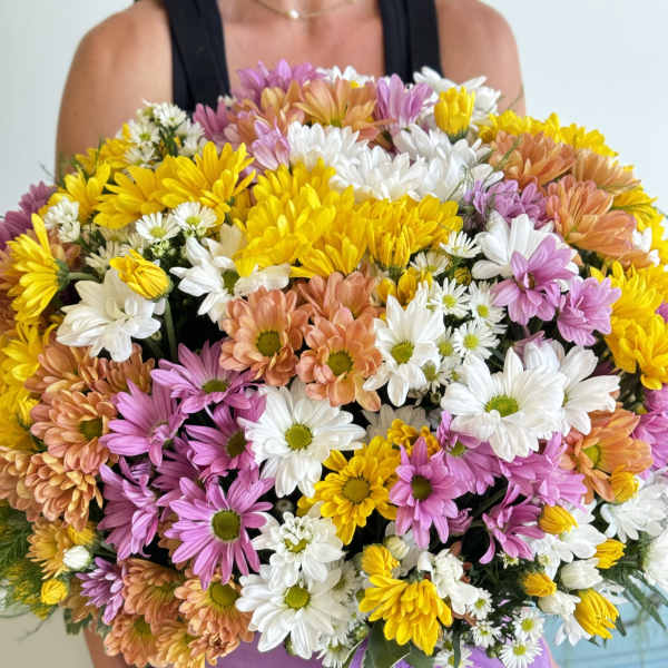 Large mixed daisy bouquet in a pink hat box with a purple ribbon