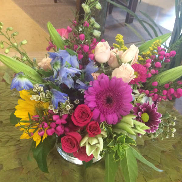 Mixed bouquet in a glass vase with pink, blue, yellow, and white flowers
