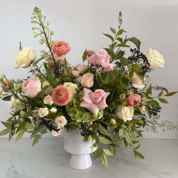 Pink and cream roses with ranunculus in a white vase