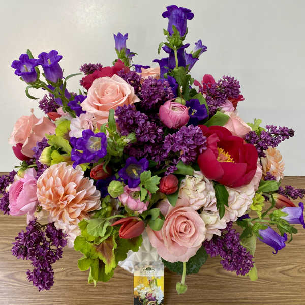 Mixed bouquet of pink, purple, and red flowers in a white vase