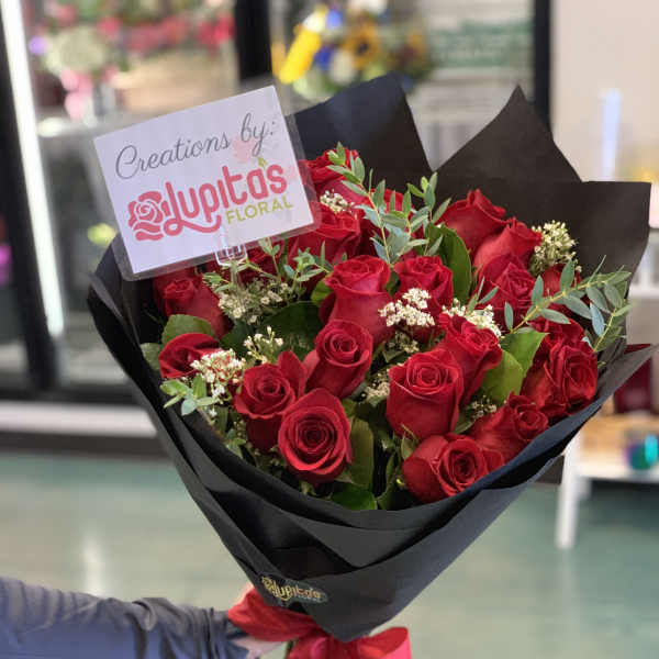 Bouquet of red roses wrapped in black paper with a red ribbon