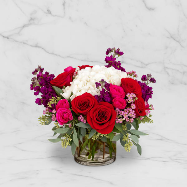 Bouquet of red, pink, and white roses in a clear glass vase