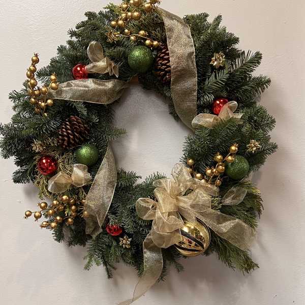 Christmas wreath with gold ribbon, ornaments, and pinecones