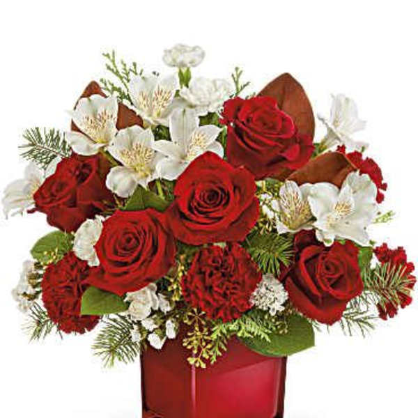 Red roses and white flowers arranged in a red glass vase