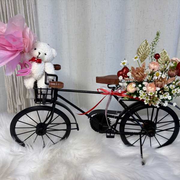 Flower-filled decorative bicycle with a teddy bear and pink bow