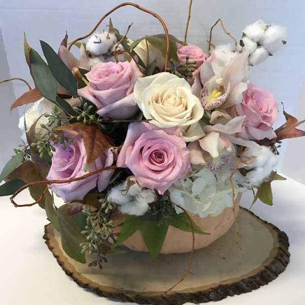 Pink and white roses arranged in a low bowl with cotton accents