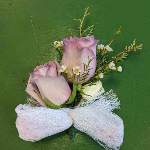 Boutonniere with lavender roses and a white ribbon bow