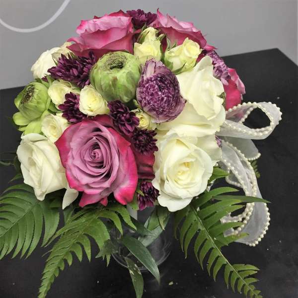 Bouquet of pink, white, and purple roses with ribbon trim