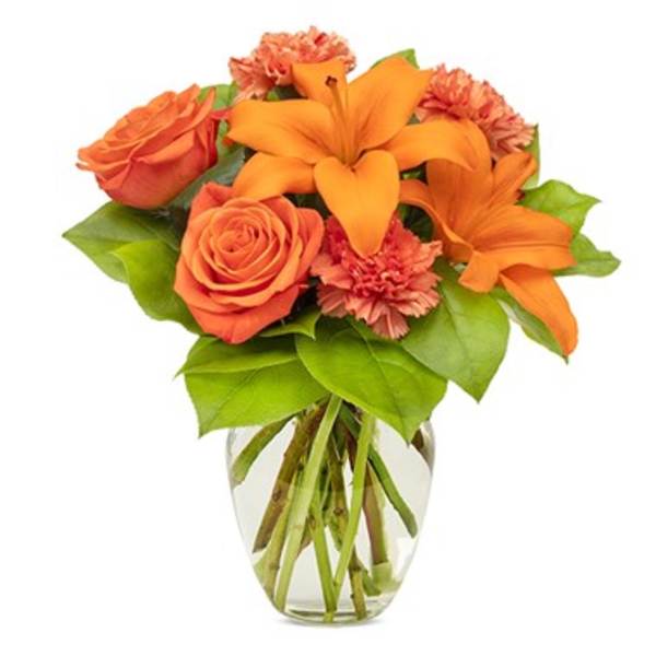 Orange roses and lilies in a clear glass vase