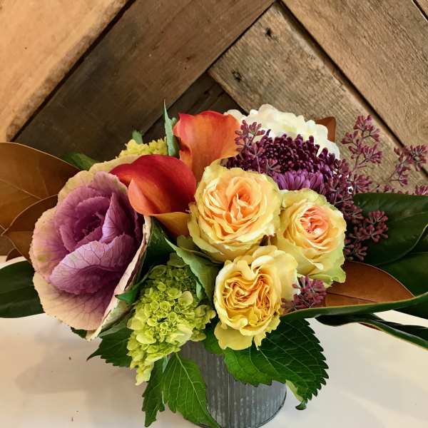 Bouquet of yellow roses, calla lilies, and purple blooms in a metal container