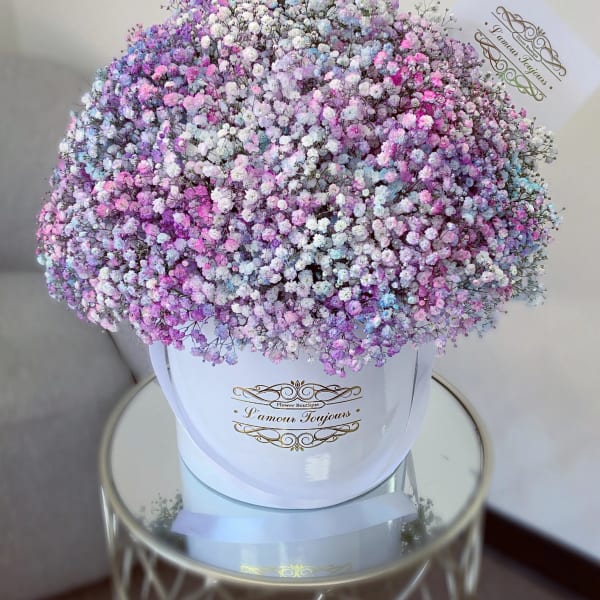 Pastel pink, lavender, blue, and white baby’s breath densely arranged in a white hatbox.