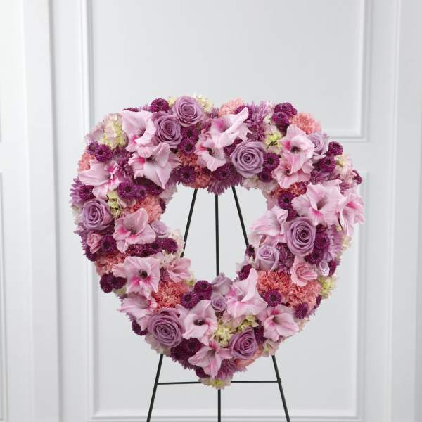 Heart-shaped pink and purple standing wreath of roses, carnations, lilies, and mums on a metal easel