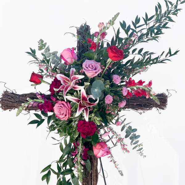Cross-shaped floral arrangement with pink and red roses and lilies