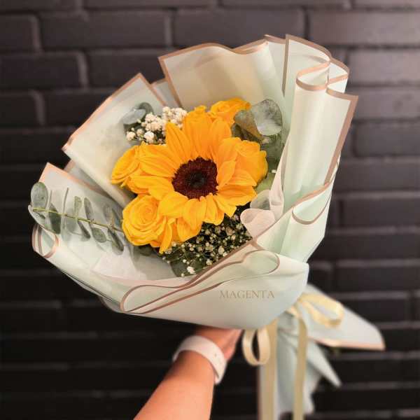 Bouquet of yellow sunflowers and roses wrapped in pale paper