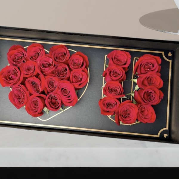 Red roses arranged to spell "I LOVE U" in a black tray