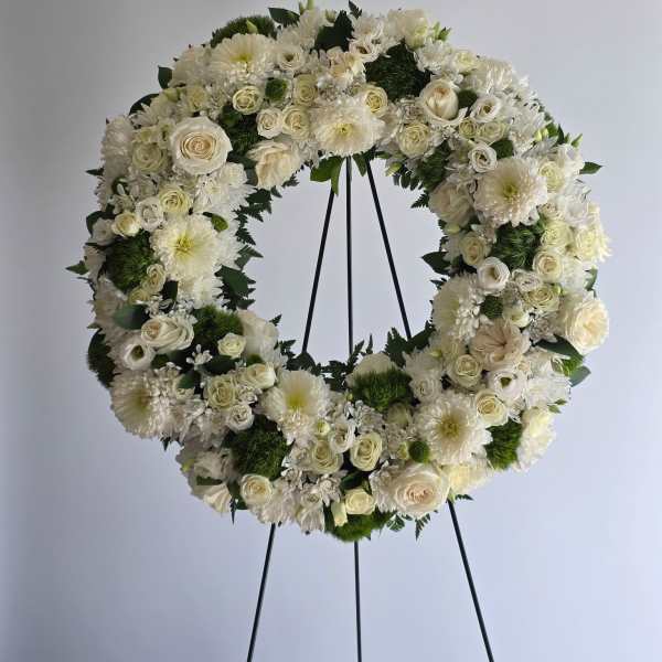 White floral wreath on a black stand