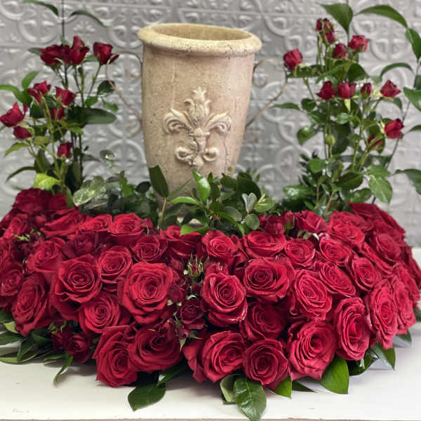 Heart-shaped red rose arrangement with a tall beige vase in the center