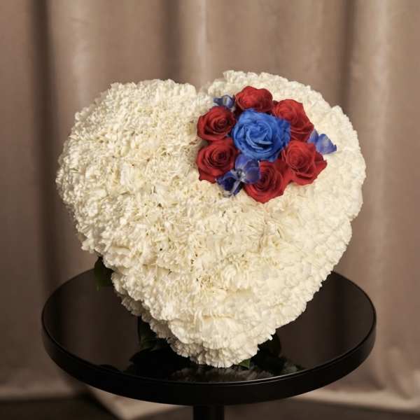 Heart-shaped white floral arrangement with red and blue roses