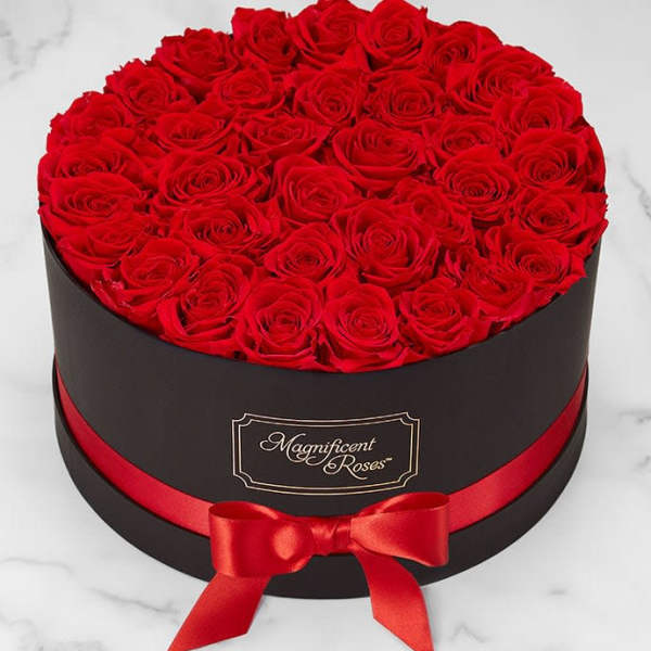 Round box filled with red roses and tied with a red ribbon