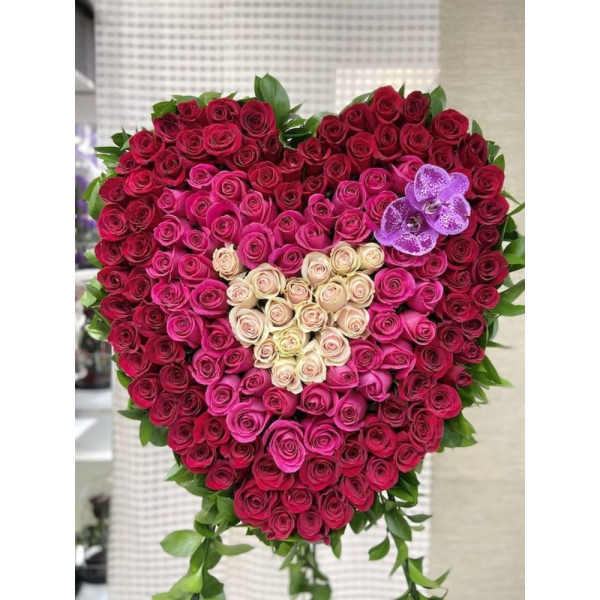 Heart-shaped arrangement of red, hot pink, and cream roses with a small inner heart and purple orchids.