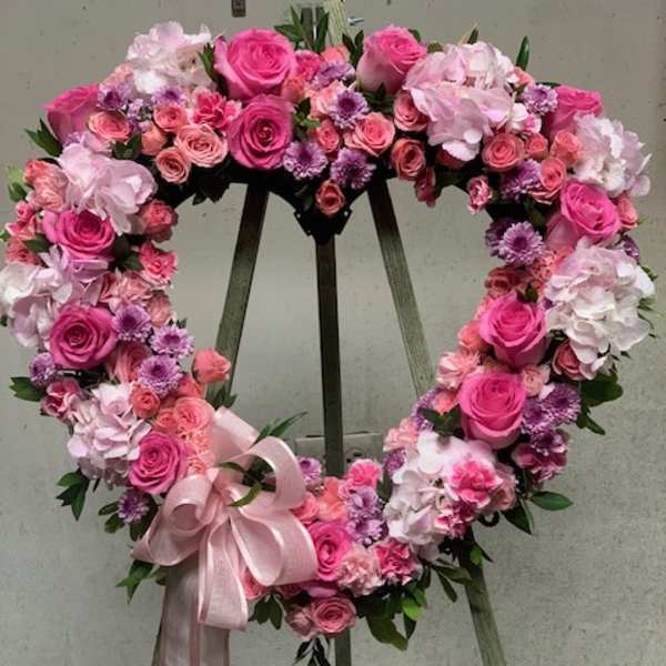 Heart-shaped floral wreath of pink roses and hydrangeas with a ribbon bow