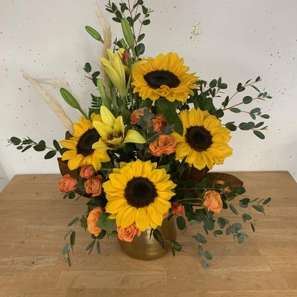 Sunflower and orange rose arrangement in a gold vase