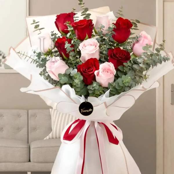 Bouquet of red and pale pink roses wrapped in white paper