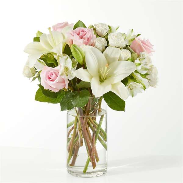 Pink roses and white lilies arranged in a clear glass vase
