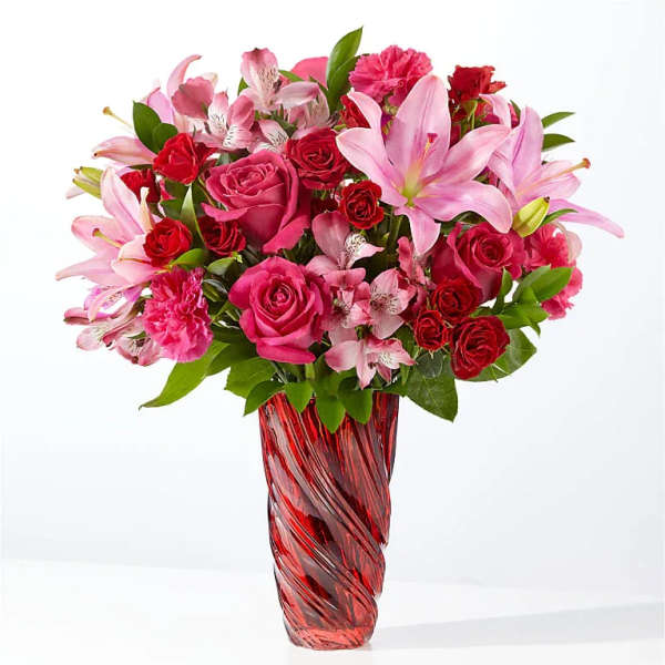 Pink and red mixed bouquet in a red glass vase