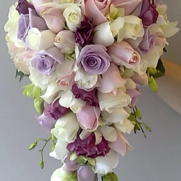 Cascade bouquet of pastel roses and orchids in pink, lavender, and white
