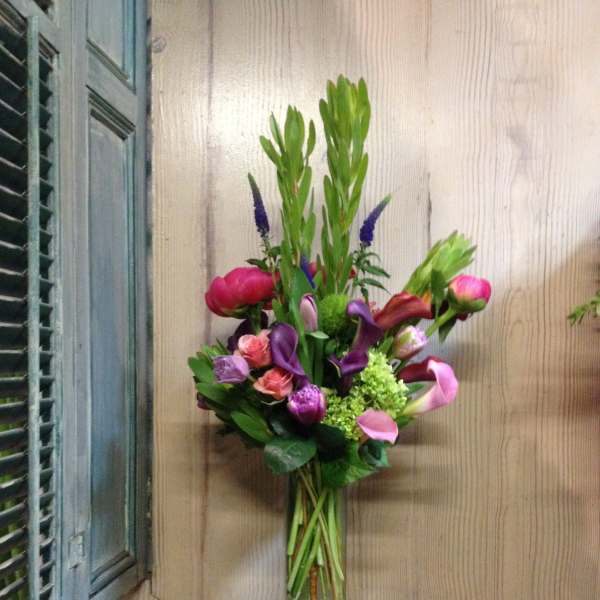 Mixed bouquet in a tall glass vase with pink, purple, and green flowers