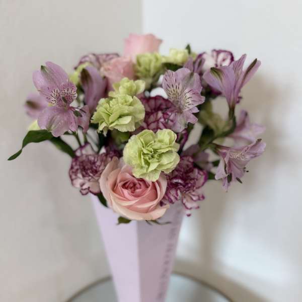 Pink and purple bouquet in a tall pale vase