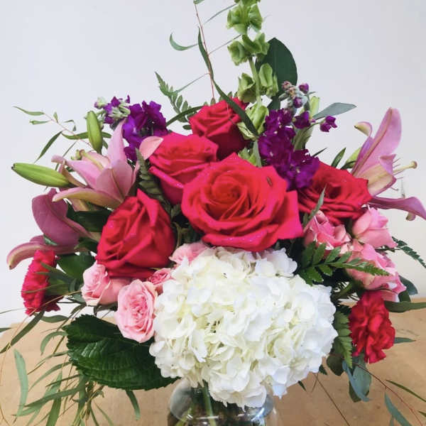 Bouquet of pink and red roses with white hydrangea in a glass vase