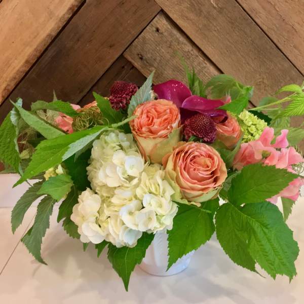 Bouquet of peach roses and white hydrangeas in a white vase