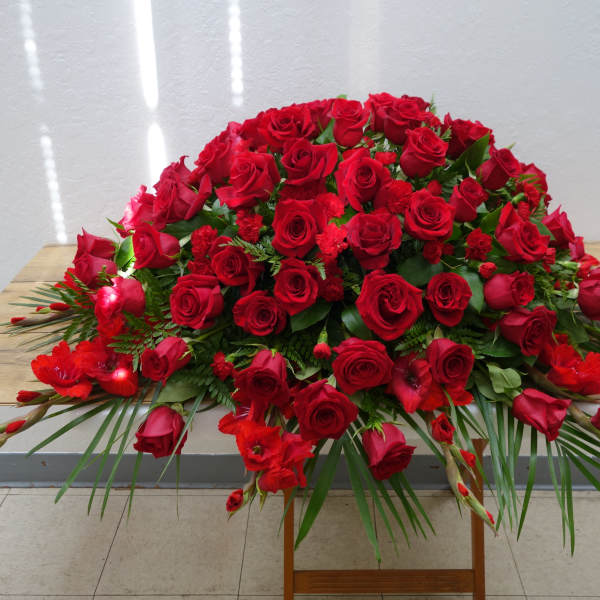 Large red rose arrangement with palm fronds on a table