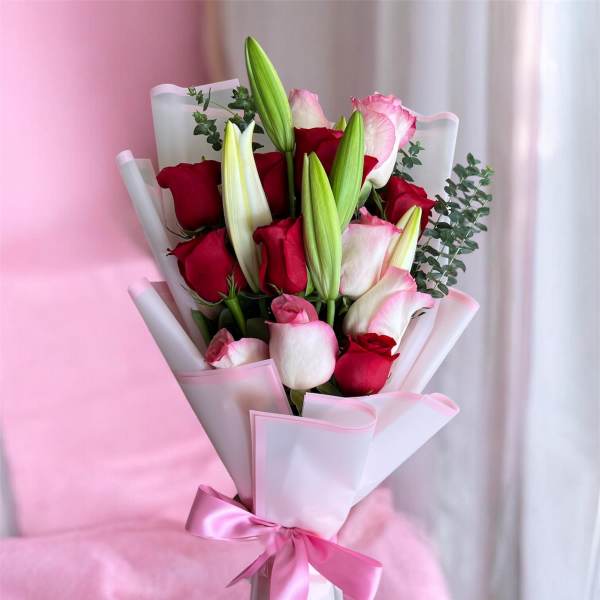 Bouquet of red and pink roses with lily buds wrapped in pink paper