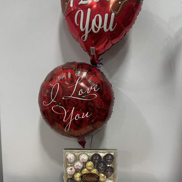 Two heart-shaped balloons with love messages above a box of Ferrero chocolates