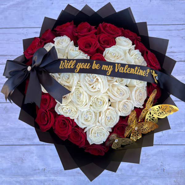 Heart-shaped bouquet of red and white roses with a black ribbon