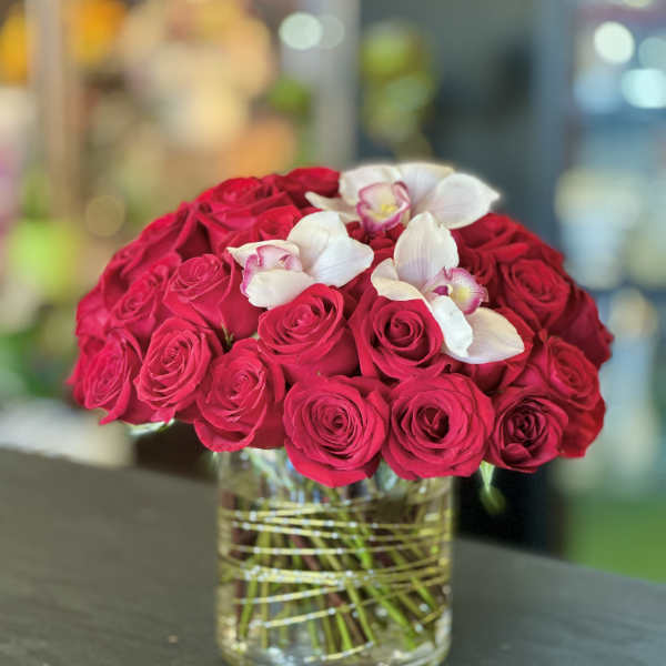Red roses with white orchids in a glass vase