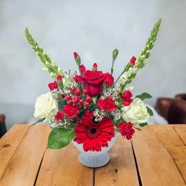 Red and white floral arrangement in a white vase