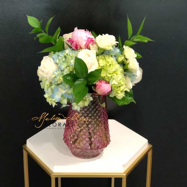 Pink and white roses with hydrangeas in a pink glass vase