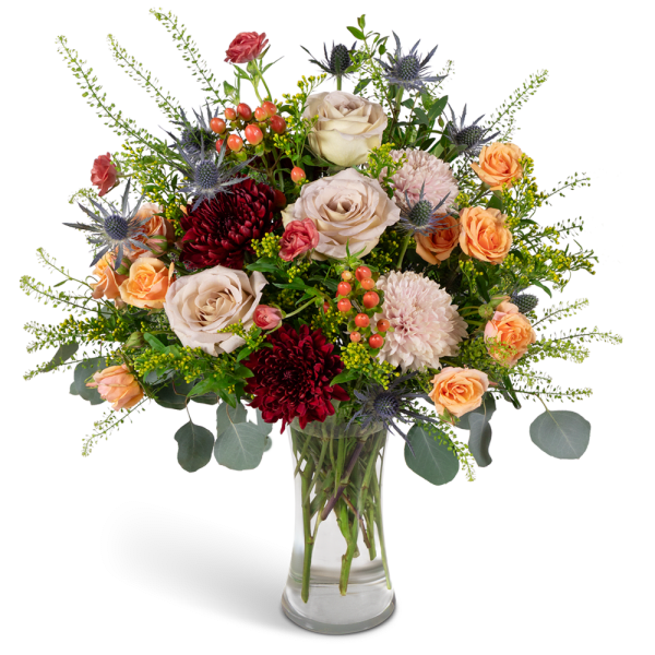 Mixed bouquet of roses, chrysanthemums, and thistle in a clear glass vase