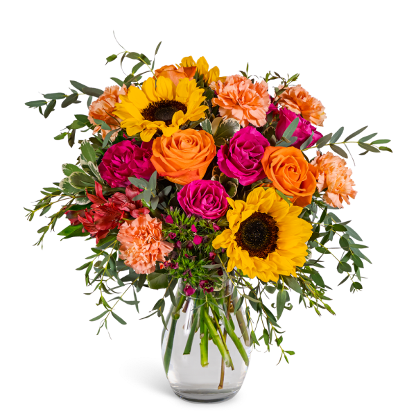 Bouquet of sunflowers, roses, and carnations in a clear glass vase