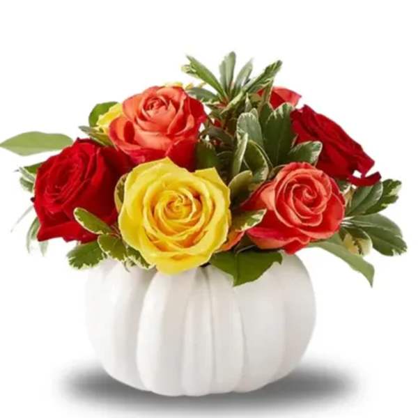 Red, yellow, and coral roses in a white pumpkin vase
