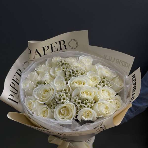 Bouquet of white roses wrapped in cream paper with a ribbon