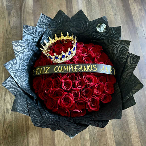 Bouquet of red roses wrapped in black paper with a small crown and birthday ribbon