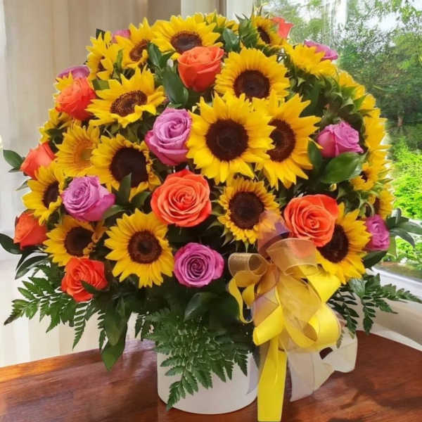 Bouquet of sunflowers and roses in a white box with a yellow ribbon